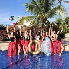 a group of women standing next to each other in front of a pool