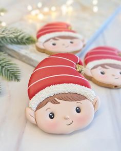 three cookies shaped like children's faces with christmas decorations on the table behind them