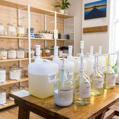 bottles of liquid are lined up on a table in a room with shelves and shelving