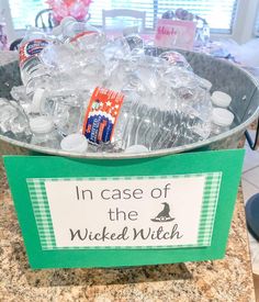 an ice bucket filled with bottles of water on top of a granite counter next to a sign that says in case of the wicken witch