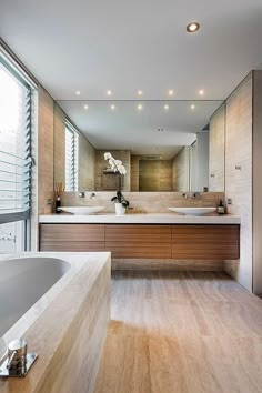 a large bathroom with two sinks and a bathtub next to a wall mounted mirror