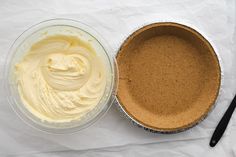 two pie pans filled with white frosting next to each other on top of paper