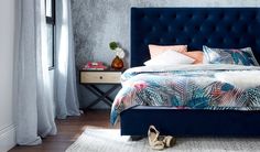 a bed with blue headboard and foot board in a bedroom next to a window