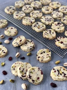 cookies and pistachios sit on a cooling rack next to a cookie sheet