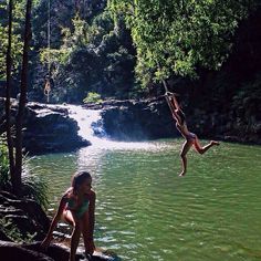 two people jumping off rocks into a river