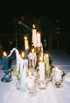 a table topped with lots of candles on top of a white table cloth covered table