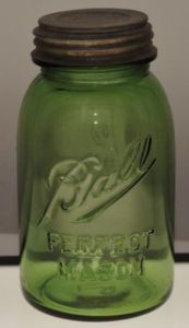 a green glass jar sitting on top of a table