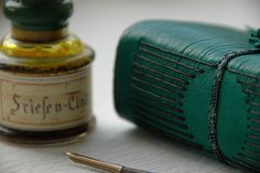 a pen sitting on top of a table next to a green bag and some ink