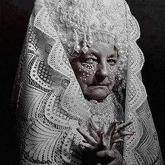 an old photo of a woman with pearls on her head and hands in front of her face