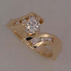 a yellow gold ring with two diamonds on the top and bottom, set against a white background