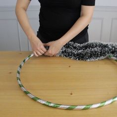 a person holding a brush on top of a wooden table next to a green and white rope