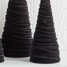 three black vases sitting on top of a white shelf