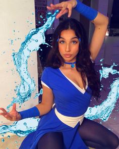 a woman dressed in blue and white posing for the camera with water splashing around her