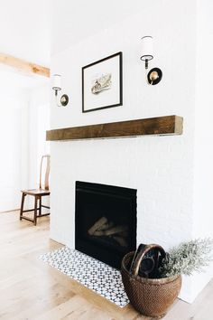 a white brick fireplace with a potted plant on the mantle and pictures above it