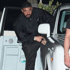 a man leaning on the door of a white car with his hand in his pocket