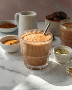 there are many bowls and cups on the table with food in them, including milkshake