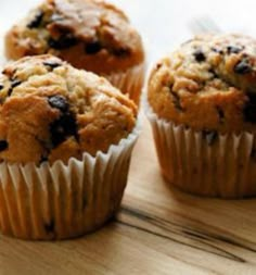 three muffins sitting on top of a wooden table