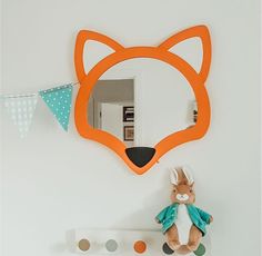 a stuffed animal sitting on top of a shelf next to a mirror and bunting