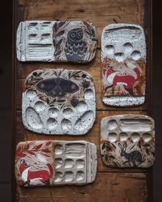 four plates with animal designs on them sitting on top of a wooden table next to each other