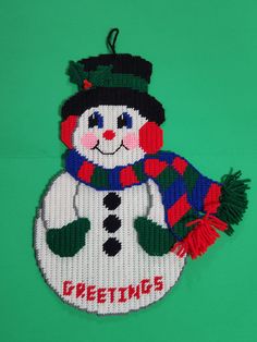 a snowman ornament is hanging on a green background with the word greetings written across it