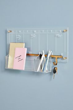 a clear plastic shelf with books and keys hanging from it's hooks on the wall