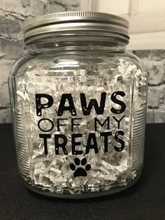 a glass jar filled with dog treats and the words paws off my treats written on it