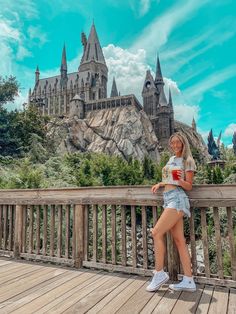 a woman standing on a wooden bridge with hogwarts castle in the back ground