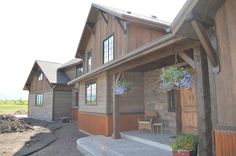 a wooden house with flowers hanging from it's front porch and side entry door