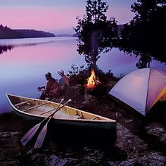 two canoes sitting next to a campfire on the shore