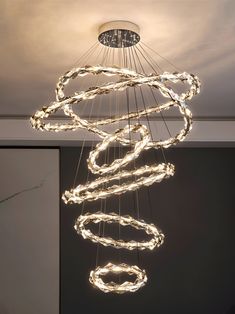 a modern chandelier hanging from the ceiling in a room with dark walls and flooring