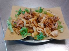 a silver plate topped with pasta covered in meat and lettuce on top of a table