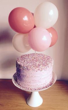 a cake with pink and white balloons on top