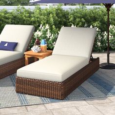 two chaise lounge chairs on a patio with an umbrella