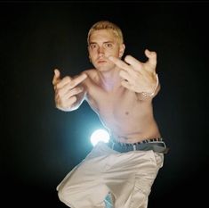 a man in white pants and no shirt doing a trick on a skateboard with his hands