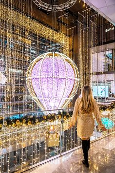 a woman is walking down the walkway in front of some christmas lights and balloons hanging from the ceiling