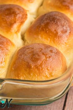 a casserole dish filled with rolls sitting on top of a wooden table