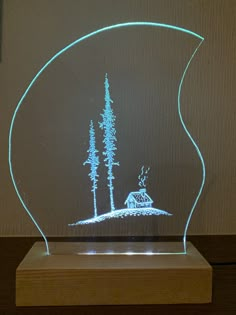 a light up glass sculpture with trees and a house in the woods on it's side