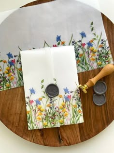 two white napkins with flowers on them sitting on a wooden plate next to wax