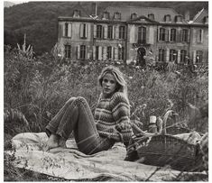 a woman sitting on top of a blanket in front of a building