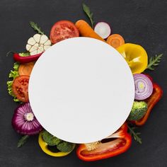 an overhead view of various vegetables with a white circle in the middle on a black background