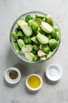 brussel sprouts and other ingredients in small bowls on a white surface