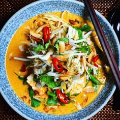 a blue bowl filled with food and chopsticks