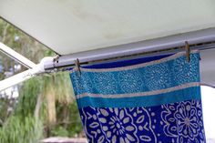 a blue and white towel hanging from the side of a awning with trees in the background