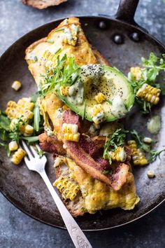 an omelet with bacon, corn and avocado on it is served in a cast iron skillet