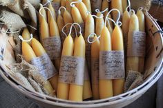 some yellow candles are in a basket with twine handles and tags attached to them