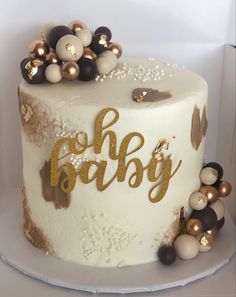 a white cake with gold and black decorations on it's top that says oh baby