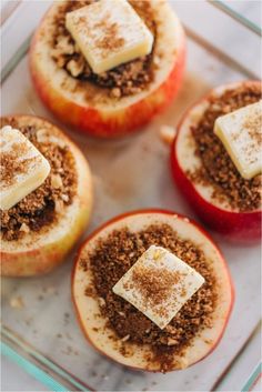 four apples with cinnamon crumbles on top in a glass dish, ready to be eaten