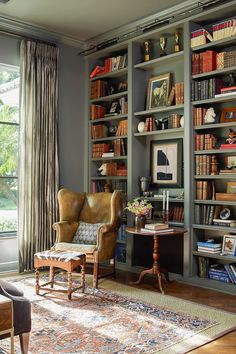 a living room filled with lots of furniture and bookshelves next to a window