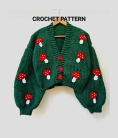 a green knitted sweater with mushrooms on the front and red dots on the back