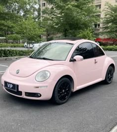 a pink volkswagen beetle parked in a parking lot